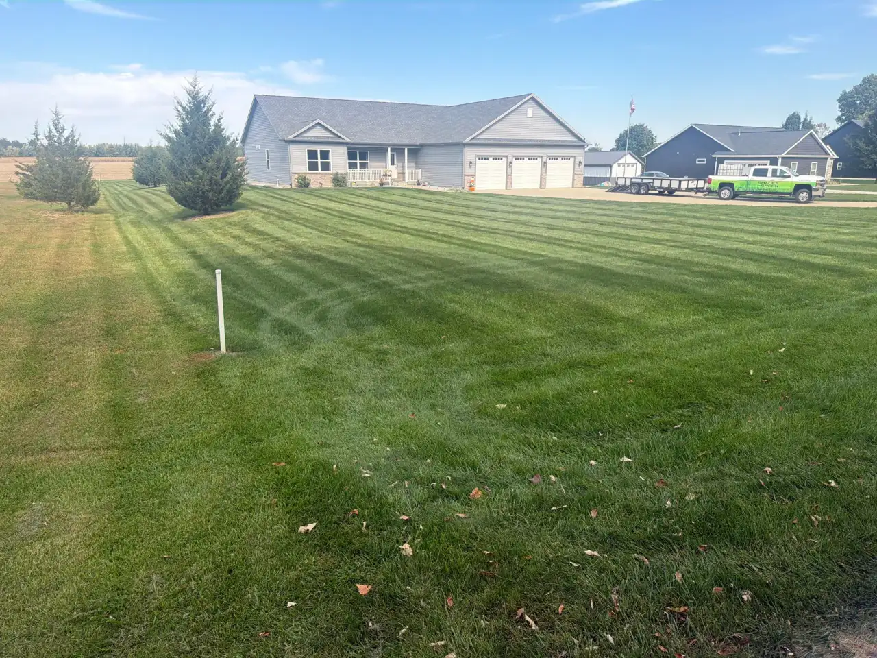 Striped front lawn of a gray ranch home with a three-car garage in Lafayette, Indiana