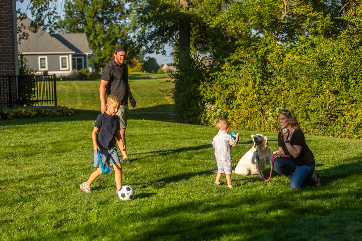 a family playing with their dog in mosquito, flea, and tick-free lawn