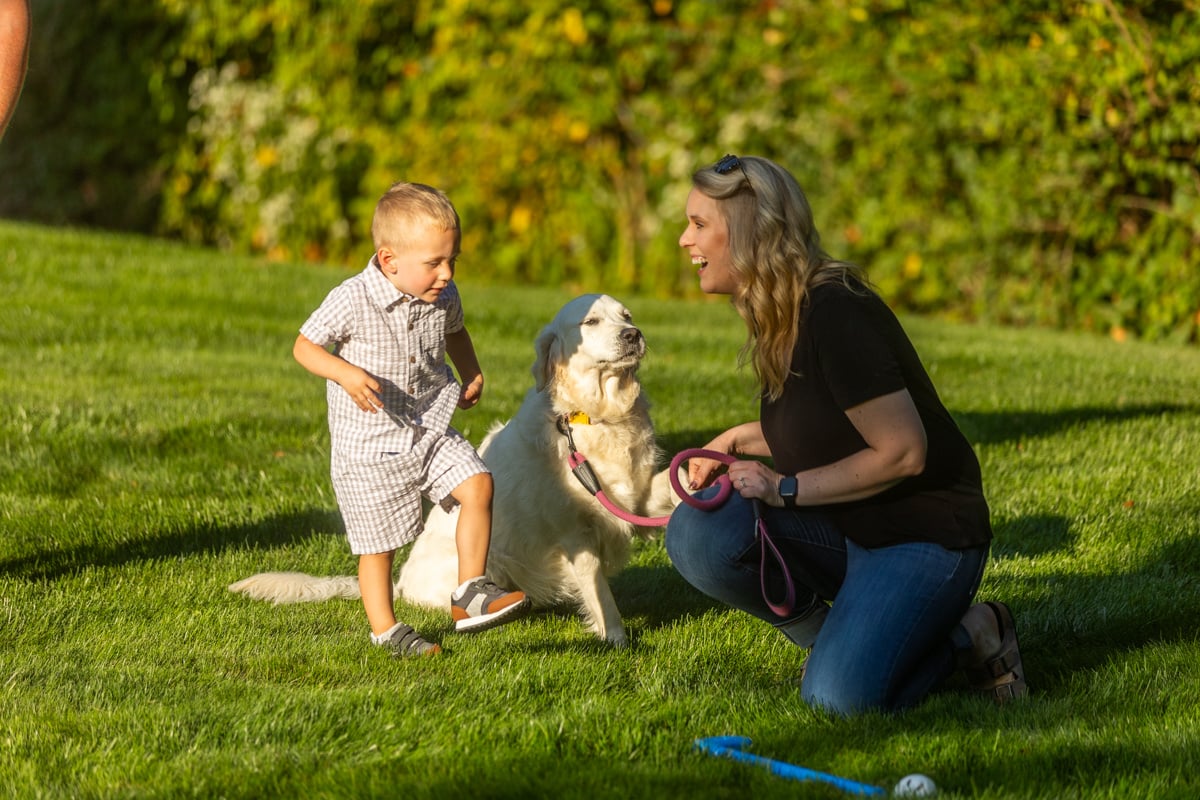 a family safely playing with their dog in the lawn