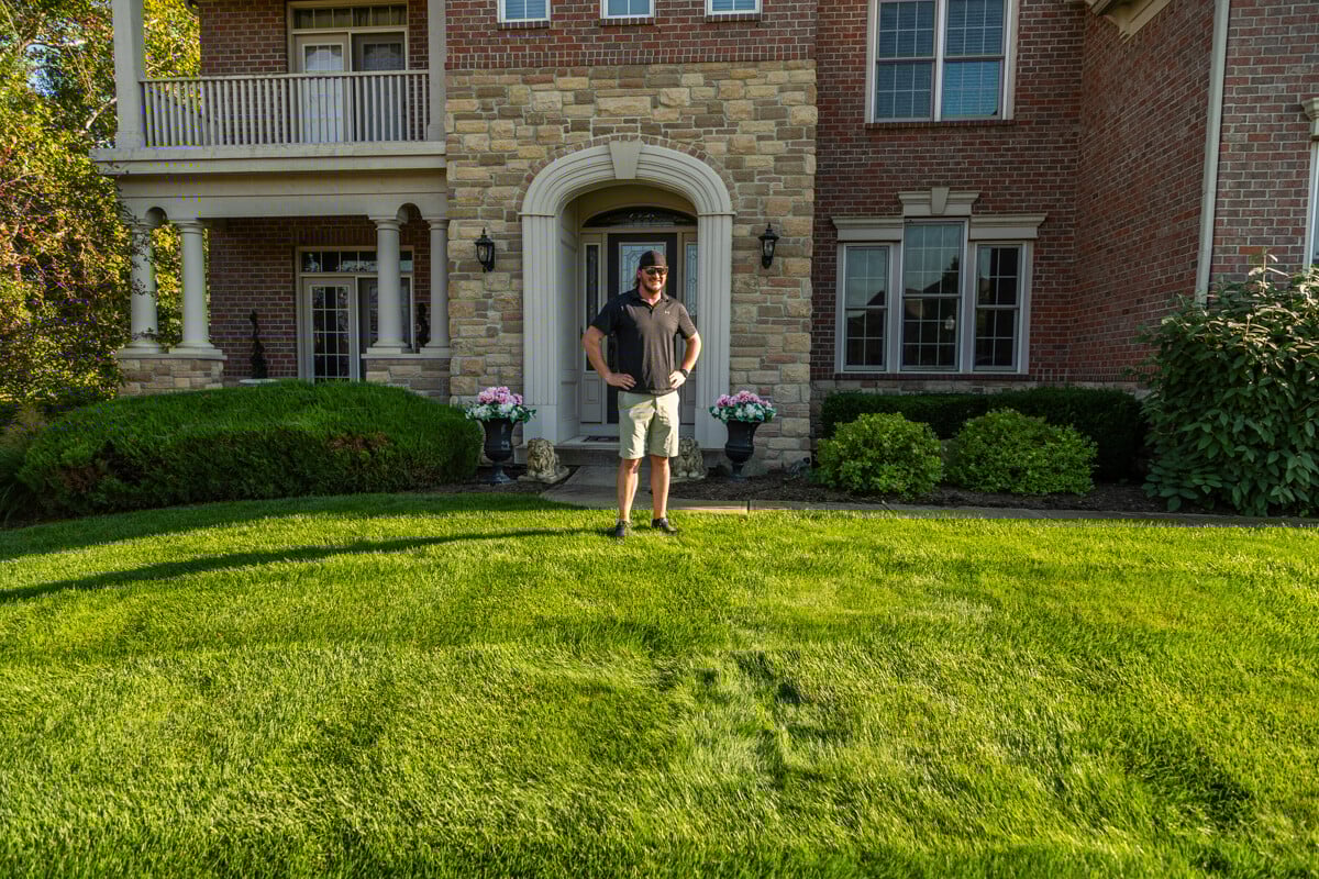 satisfied lawn care customer standing on their green grass