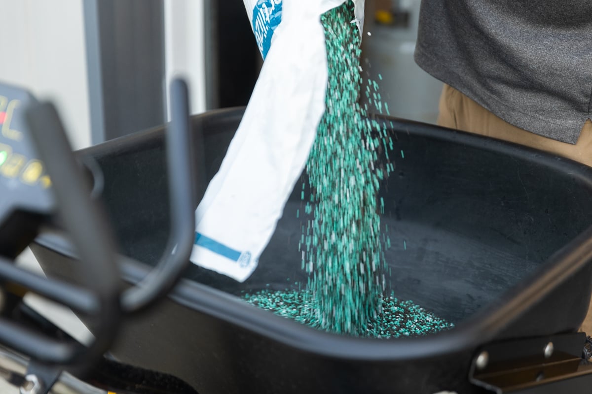 polymer-coated granular fertilizer being poured into a hopper