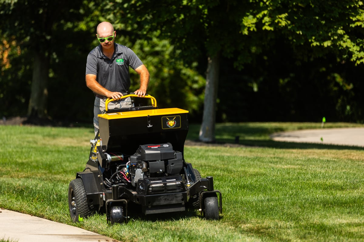 lawn care technician aerating the soil to help the health of the lawn