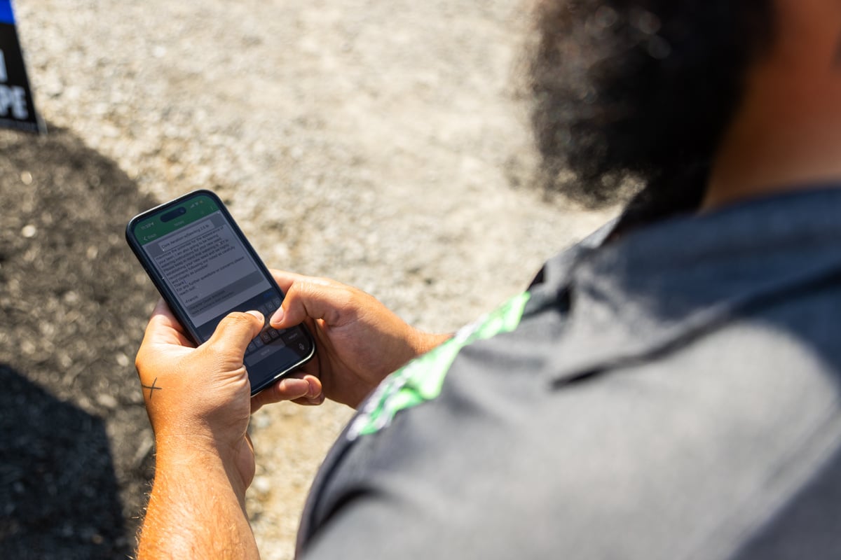 lawn care tech checking phone for service notes