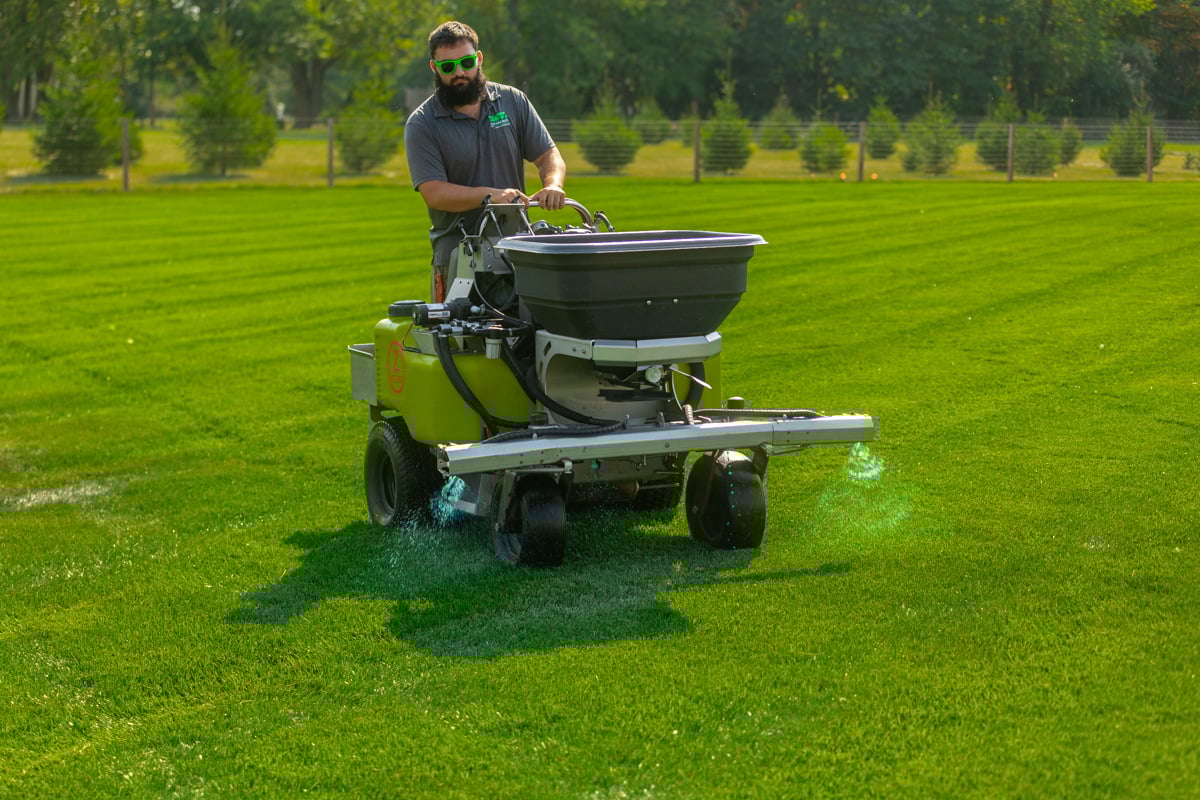 professional lawn care technician applying a liquid treatment to a lawn