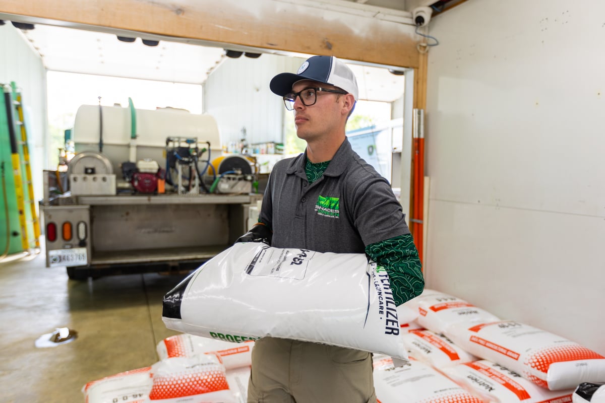 lawn care tech loading bags of winter fertilizer for application