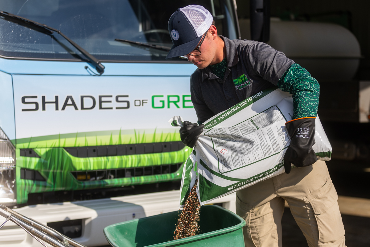 lawn care technician loading a hopper with a custom blended fertilizer